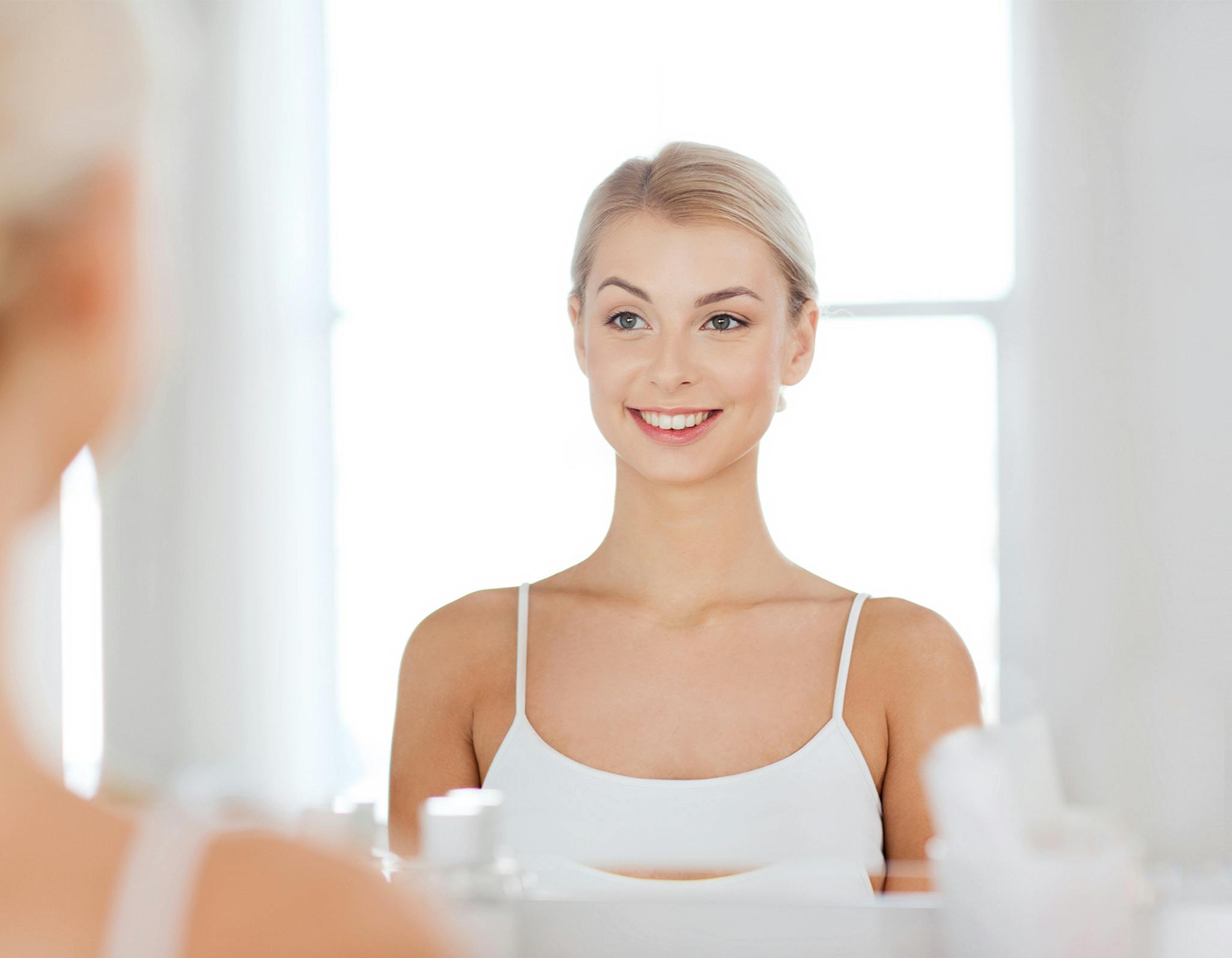 Young woman smiles and stands in front of the mirror