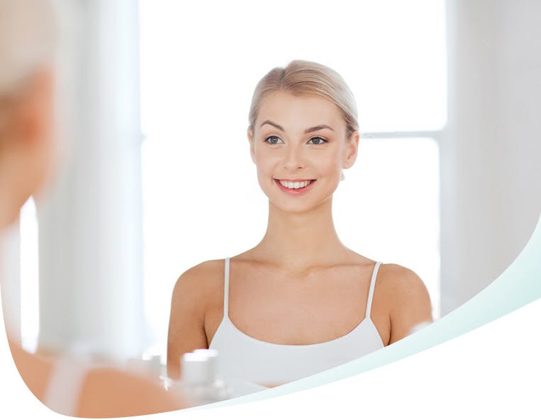 Young woman smiles and stands in front of the mirror