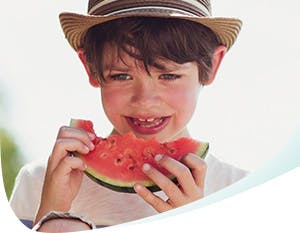 Garçon portant un chapeau mangeant du melon d'eau acide