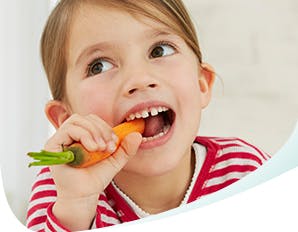 Young girl biting into a carrot