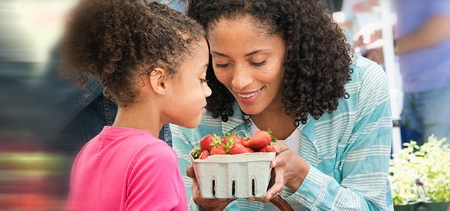 Une femme et sa fille examinent des fraises.
