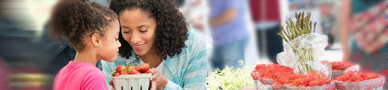 Une femme et sa fille examinent des fraises.