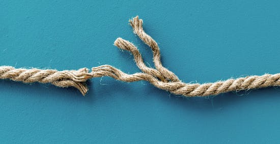 Piece of rope almost completely cut in half except for a few final threads Piece of rope almost completely cut in half except for a few final threads