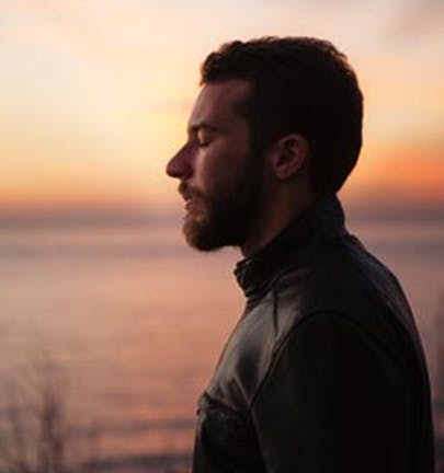 Man meditating outside by a lake during a beautiful sunrise Man meditating outside by a lake during a beautiful sunrise