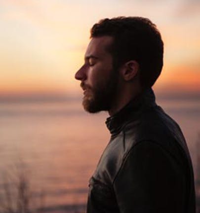 Man meditating outside by a lake during a beautiful sunrise