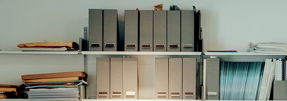 Two wall shelves full of work-related binders and paperwork