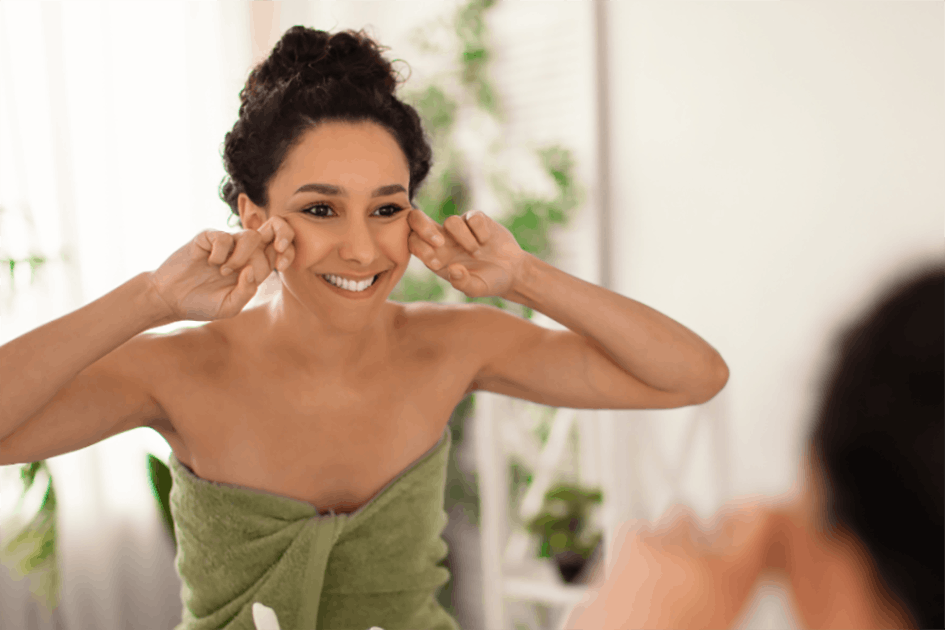 Smiling woman applying skincare at her sink 