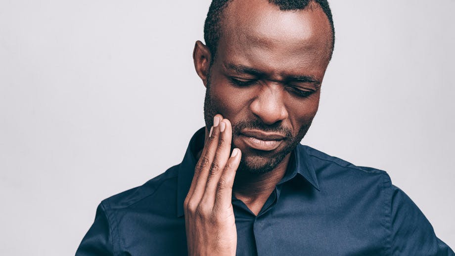 Man holds side of his face, indicating tooth pain