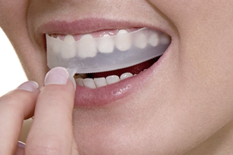 Woman using whitening strips on her sensitive teeth