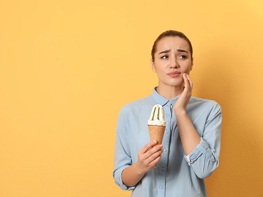 A white woman experiencing sensitive teeth with ice cream