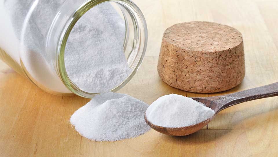 Baking soda in an unmarked jar being measured for use.