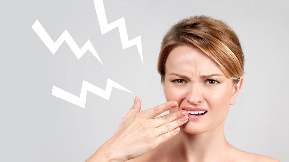 Young woman drinking water experiencing sensitive teeth