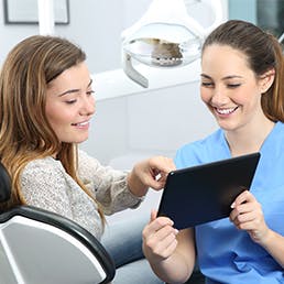 Dentist using a tablet to discuss treatment with a female patient
