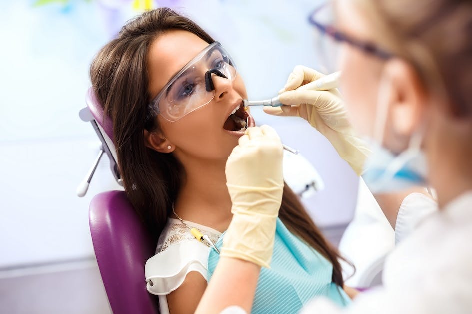 Dentist cleaning patient’s teeth in dental office