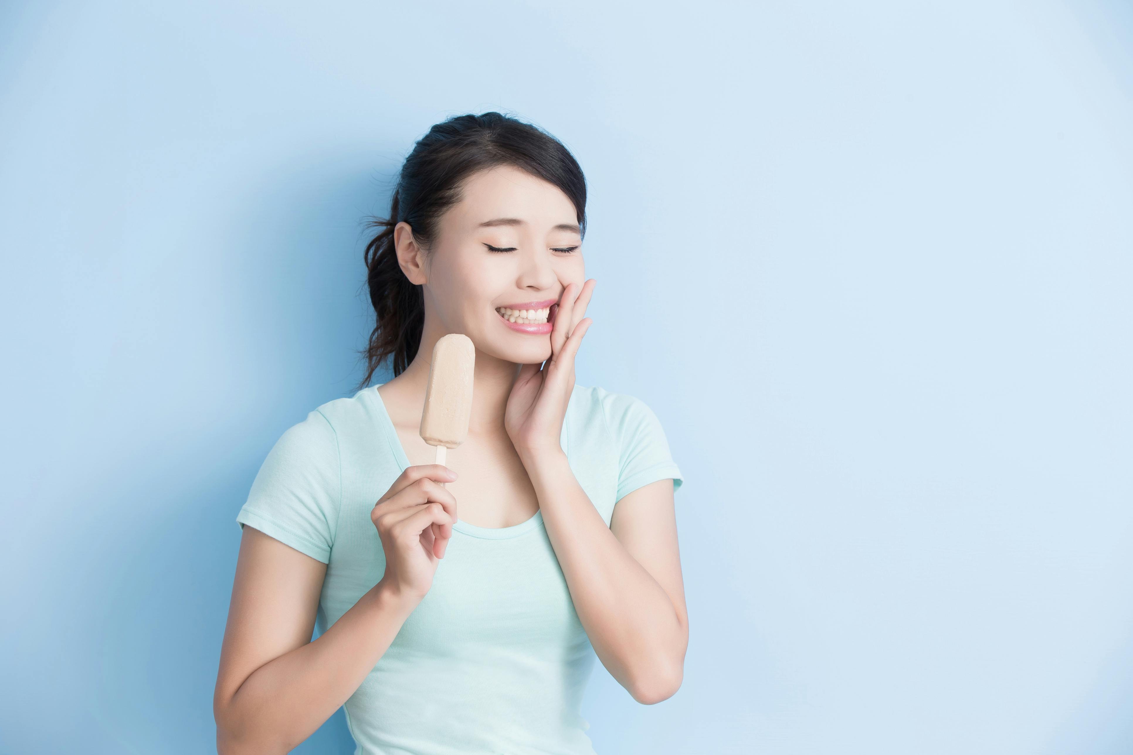 Woman feeling tooth sensitivity while holding an ice cream bar