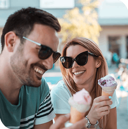 Smiling young couple sitting outdoors and eating ice cream