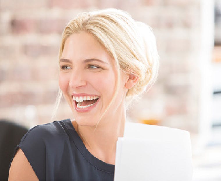 Kvinde smiler, fordi hun lige er færdig med at blege sine følsomme tænder