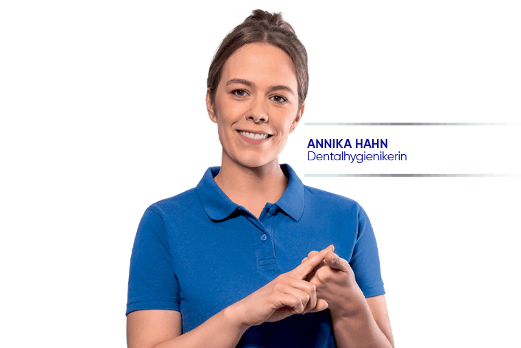 Dentalhygienikerin Annika Hahn lächelt im blauen T-Shirt auf hellem Hintergrund.