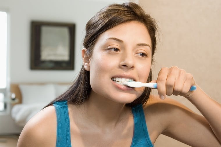 Woman flossing her teeth in the mirror