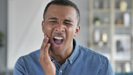 Image of a man holding his jaw in pain with toothache