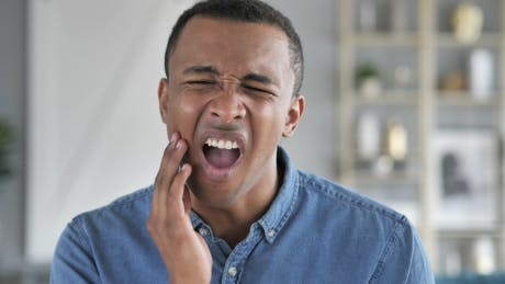 Image of a man holding his jaw in pain with toothache Image of a man holding his jaw in pain with toothache