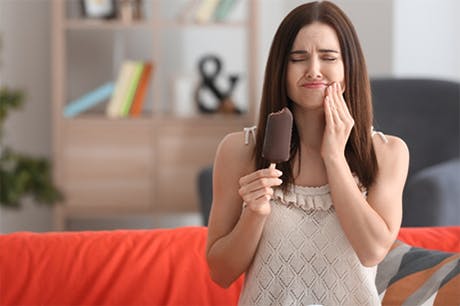 A woman with ice cream is experiencing tooth pain