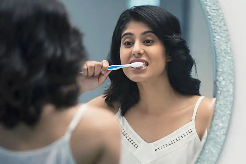 Young woman brushing her teeth with Sensodyne toothpaste for sensitive teeth