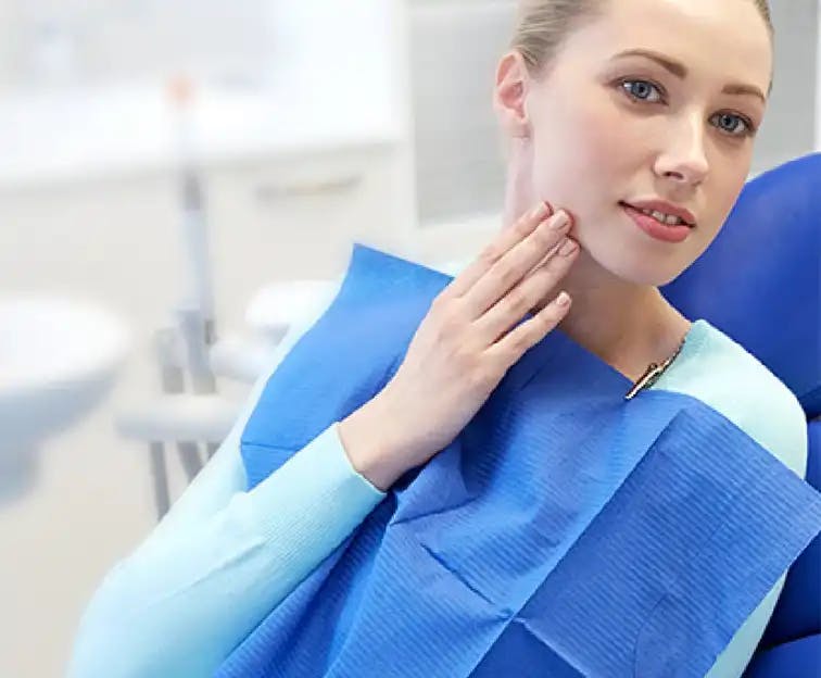Woman in dental chair touching her jaw