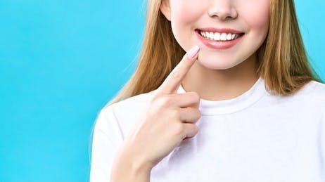 Une femme montre du doigt des dents blanches