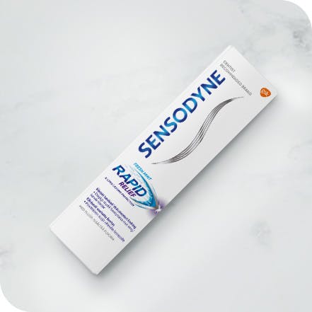 Sensodyne tannkrem og tannbørste som ligger på en benk