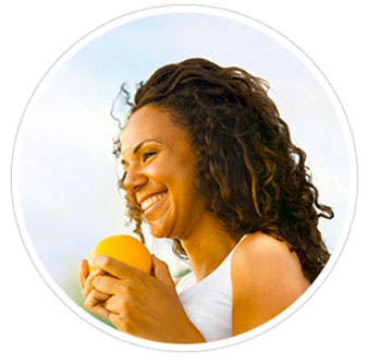 A woman smiling holding an orange in her hands