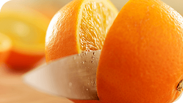 Fresh orange being sliced in half with a knife