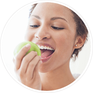 A girl just about to bite into a gren apple