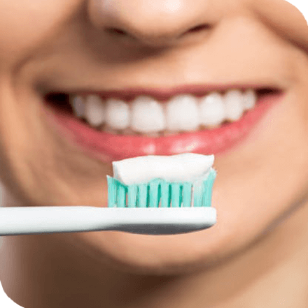 Toothpaste on a toothbrush in front of a smiling woman