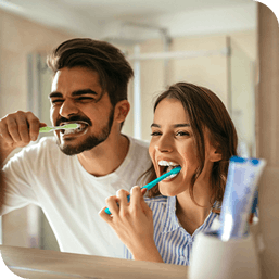 Young couple brushing their teeth together while looking in a mirror