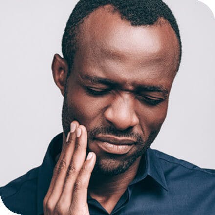 Young man holding his jaw from tooth pain.