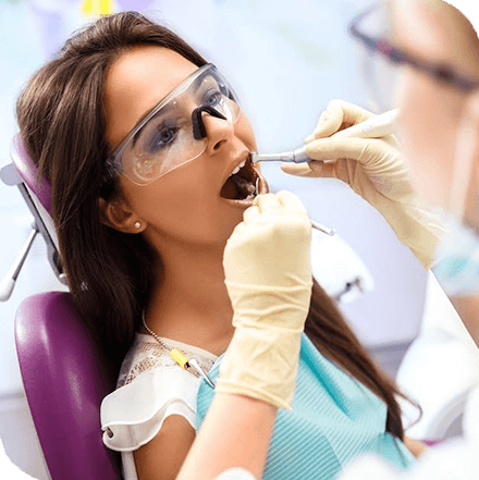 dentist cleaning patient’s teeth in dental office