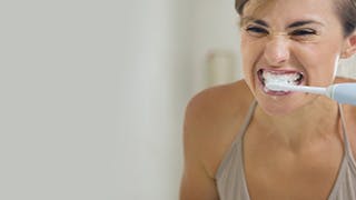 Vrouw die tanden poetst met Sensodyne tandpasta.