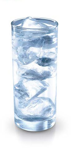 Glas water met ijsklontjes. Kou kan gevoelige tanden triggeren.
