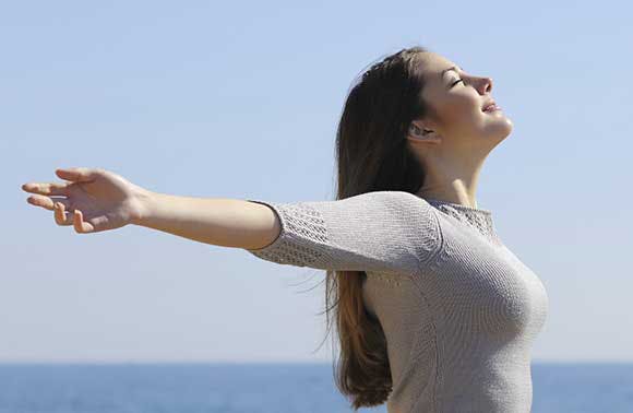 Woman with outstretched arms breathing in the air