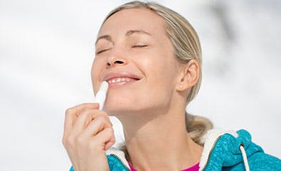 Young woman applying lip balm