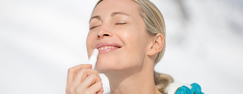 Young woman applying lip balm
