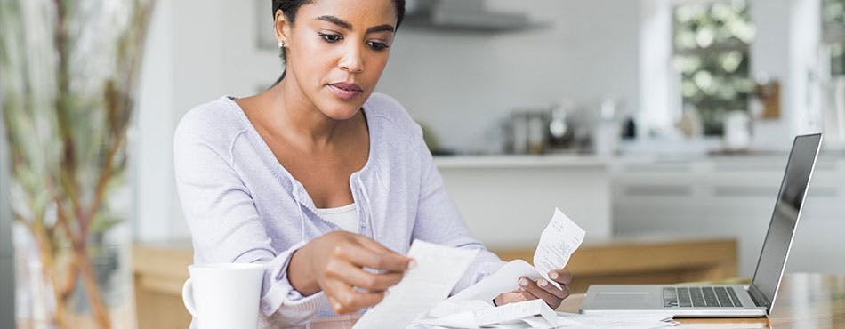 Woman sitting at a desk and reviewing receipts | Create a budget.