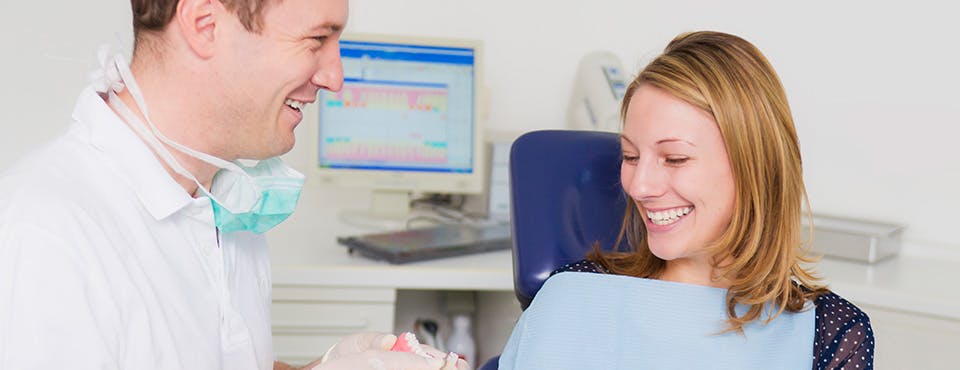 Dentist professional and a woman smiling and talking Dentist professional and a woman smiling and talking