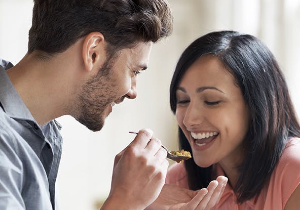 Man sharing his food with a woman from a spoon