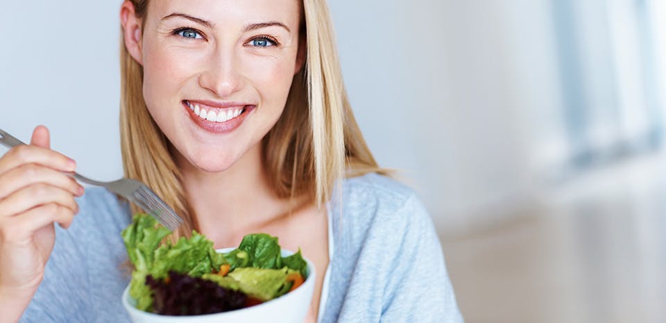 Woman smiling and holding a bowl with salad | Eat fresh