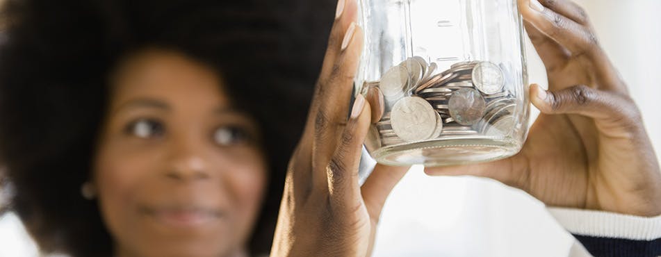 Woman holding a coin jar | Follow the 50/30/20 rule