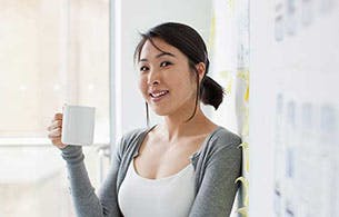 A woman smiling and holding a cup of coffee