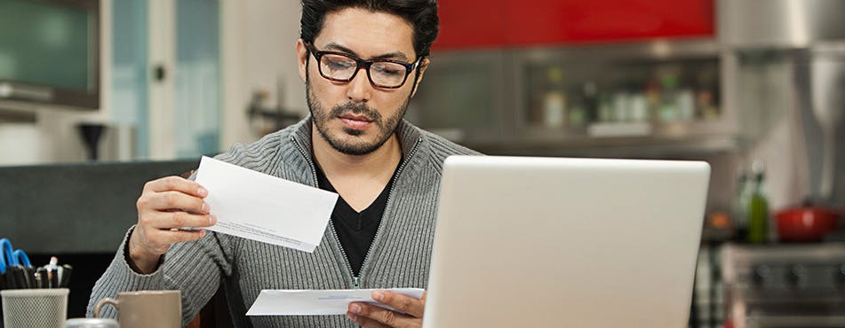 Man sitting at a desk and reading mail | Review your budget every month.