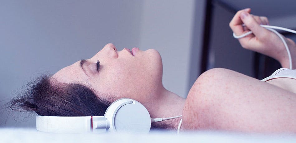 Woman sleeping and listening to music | Stick to a bedtime routine